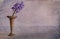 Single Bluebell  in old metal vase textured painterly image with room for text, concept spring