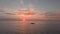 Single boat in ocean against sun path at dawn. Cinematic drone shot