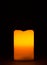 Single burning candle with warm orange red halo