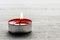 Single burning red tealight candle