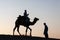 Single camel rider and person standing silhouetted dusk twilight