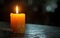 A single candle burning brightly in a dark room, casting a gentle glow. The candle symbolizes remembrance and awareness
