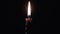 A Single Candle is Lit on a Black Background. Candle Flame in the Dark.