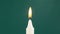 A Single Candle is Lit on a Green Background. Lighting. Candle Flame