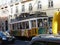 Single car yellow tram of no. 28 in Lisbon with street traffic