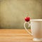 Single cherry on cup handle on grunge background