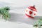 Single Christmas decorative trinket. Red white glass ball with heart shapes. Fir twig with frosted cone. Sunlight, long