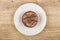 Single cookie with chocolate in white saucer on wooden table