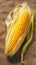 Single corn cob on brown sackcloth background, viewed from side