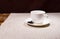 Single cup and saucer with spoon on tablecloth