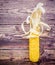 Single curly drying corn cob on dark wooden background flat lay top view