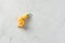 A single curved yellow sugar rush peach pepper sits on a white marble background with copy space