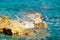 Single deck chair standing on a rock middle of the sea