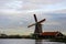 A sIngle dutch windmill with a traditional wooden house in a Netherland`s landscape.
