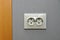 Single empty electrical outlet on a gray wall by the doorway