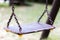 Single empty old swing on metal chain in child playground close