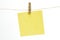Single empty paper sheet for notes that hang on a rope with clothespins and isolated on white. Blank yellow cards on rope mockup
