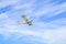 Single engine ultralight plane flying in the cloudy blue sky