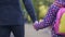 Single father and daughter holding hands and walking forward together, autumn