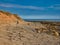 A single female walker crosses a  wave cut platform of limestone at Seahouses on the Northumberland coast on a sunny day