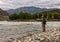 Single fisherman on a stormy river is fishing on a sunny summer day