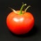 Single fresh juicy red bunch tomato on black background