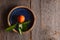 A single fresh picked Minneola Tangelo ina blue plate with orange blossoms and leaves, on a rustic wood table with copy space