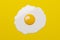 Single fried egg on yellow background flat lay top view from above, food, diet or breakfast concept