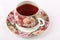Single full porcelain teacup with hot tea and with floral pattern on a white cloth