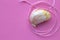 A single garlic with sewing needle and a pink Spool Of Pink Sewing Thread With Needle and pink background on the right side