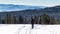 Single girl descending from the top of the mountain straight into a forest, during a beautiful sunny winter day