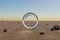 single glas ring hovering in the air in large empty desert environment abstract surreal concept 3D Illustration