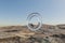 single glas ring hovering in the air in large empty desert environment abstract surreal concept 3D Illustration