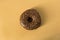 Single glazed chocolate donut on gold background - minimalism, copy space