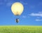 Single glowing lamp balloon flying over green meadow with sky