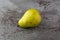 Single green anjou pear on a gray mottled background side view