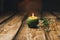 Single green ball-shaped candle with a dry flower burning on a rustic wooden table close-up