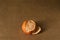 A single half-peeled clementine on brown paper