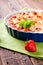 Single harvested strawberry in front of fruit pie in blue bowl on green towel