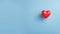 A single heart-shaped balloon on a blue background, copy space