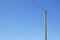 A single high voltage power line against blue cloudless sky.