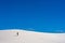 Single Hiker Crosses White Sand Dune Under Blue Sky
