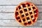 Single homemade cherry pie over a rustic white wood background