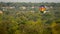 Single hot air balloon floats over the city of trees over a blanket of green