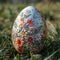Single, intricately decorated Easter egg on bed of spring grass