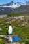 Single King Penguin standing enjoying the sun next to a small pond, part of a large King Penguin colony in the beautiful landscape