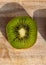 Single kiwi slice on a wooden board