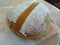 Single Krapfen italian doughnut covered with icing sugar on napkin