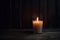 single lit candle in a dimly lit room