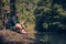 Single male hiker using tablet on nature while sitting on rocky river shore